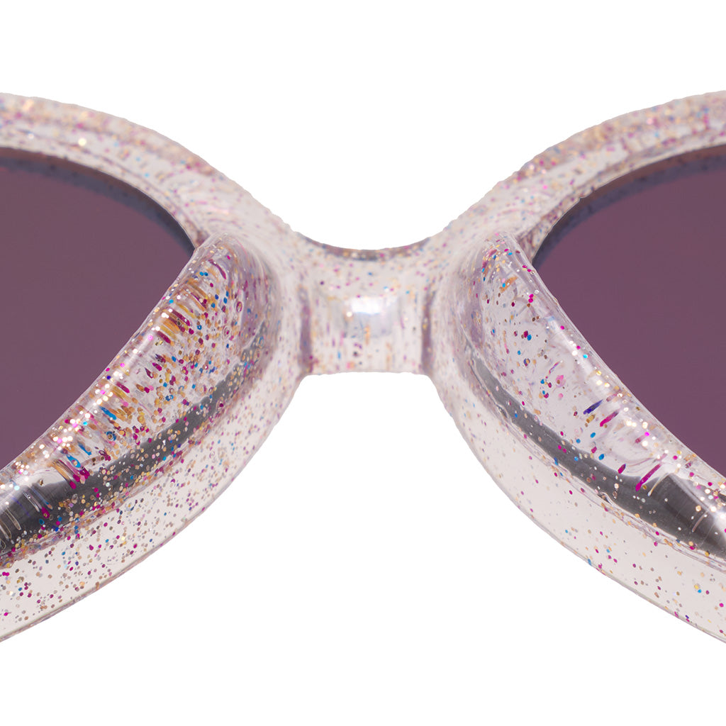 A closeup of the nose bridge of clear rainbow specked sunglasses.