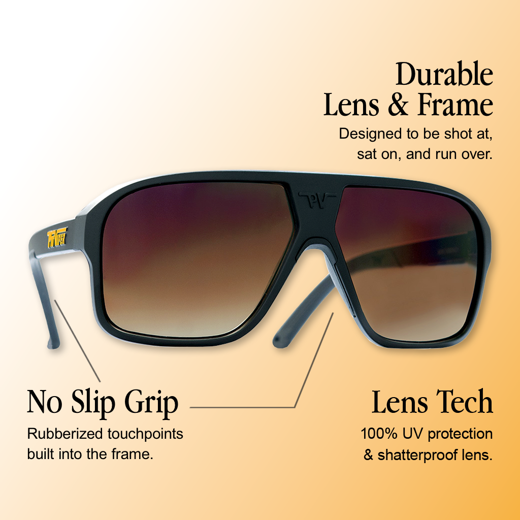 Infographic for Pit Viper Flight Optics sunglasses showing a side/three-quarter view of large matte black aviator-style frames with a brown-to-amber gradient lens, a gold 'PIT VIPER' logo on the temple, and a 'PV' emblem on the lens bridge, on a white-to-tan gradient background, with 3 callouts: 'Durable Lens & Frame - Designed to be shot at, sat on, and run over.', 'No Slip Grip - Rubberized touchpoints built into the frame.', 'Lens Tech - 100% UV protection & shatterproof lens.'