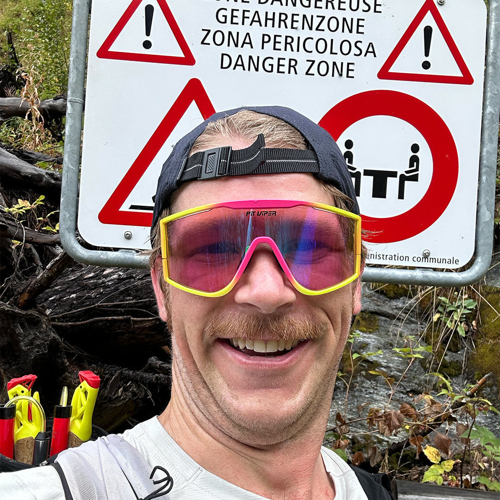 Man smiling in front of a sign wearing the Italo Try-Hard from Pit Viper Sunglasses