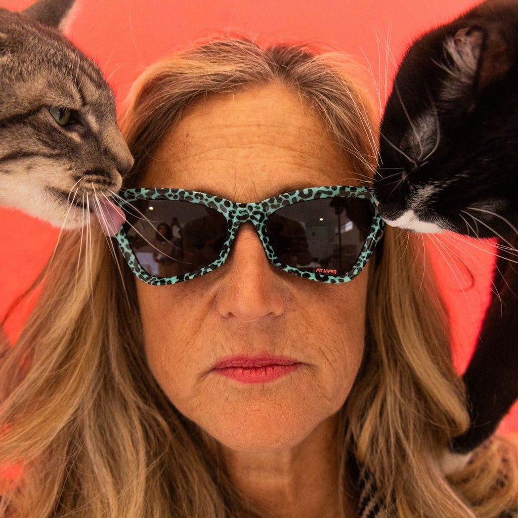 Women wears The Marissa’s Nails Clawdia with a smoke lens from Pit Viper. Cat licks the lens