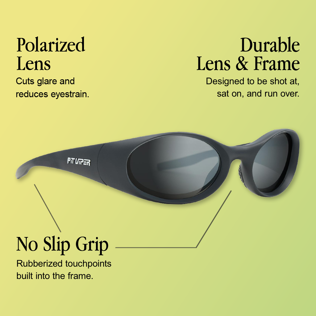 Infographic for Pit Viper Slammer Polar sunglasses showing a side-angle view of an all-black matte rounded wraparound goggle-style frame with dark polarized lenses and a white 'PIT VIPER' logo on the temple arm, set against a yellow-to-green gradient background, with 3 callouts: 'Polarized Lens - Cuts glare and reduces eyestrain.', 'Durable Lens & Frame - Designed to be shot at, sat on, and run over.', 'No Slip Grip - Rubberized touchpoints built into the frame.'